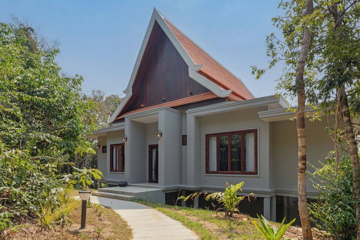 A modern house with a sloped roof, a front porch, and a pathway leading to the entrance.