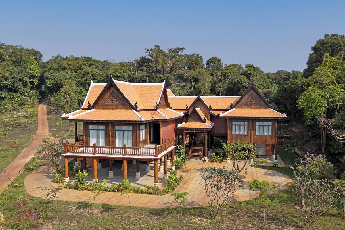 A traditional wooden house with multiple rooms, a porch, and a staircase leading to the upper floor.
