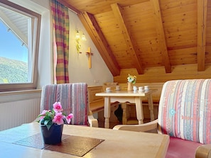 A cozy room with a wooden ceiling, a table with a vase of flowers, and a bench. - Katschberg 26 by Interhome (Sankt Michael im Lungau)