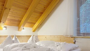 A bedroom with a wooden ceiling, a bed with white bedding, and a window with a sheer curtain. - Katschberg 26 by Interhome (Sankt Michael im Lungau)