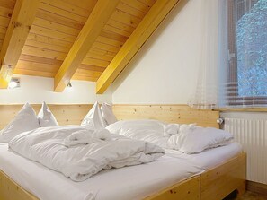 A bedroom with a wooden ceiling, a bed with white bedding, and a window with a sheer curtain. - Katschberg 26 by Interhome (Sankt Michael im Lungau)
