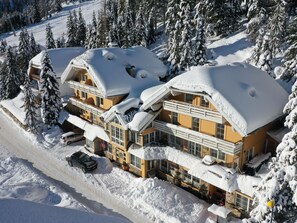 A multi-story hotel with snow-covered roofs and a ski slope in the background. - Katschberg 25 by Interhome (Sankt Michael im Lungau)
