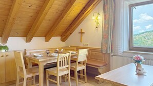 A cozy dining area with wooden furniture, a cross on the wall, and a window with a view of the outdoors. - Katschberg 25 by Interhome (Sankt Michael im Lungau)