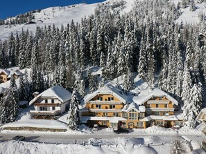 Een besneeuwde lodge met meerdere gebouwen, omringd door dichte altijdgroene bomen.