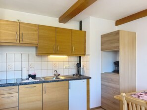 A compact kitchen with wooden cabinets, a built-in dishwasher, and a coffee machine. - Katschberg 23 by Interhome (Sankt Michael im Lungau)
