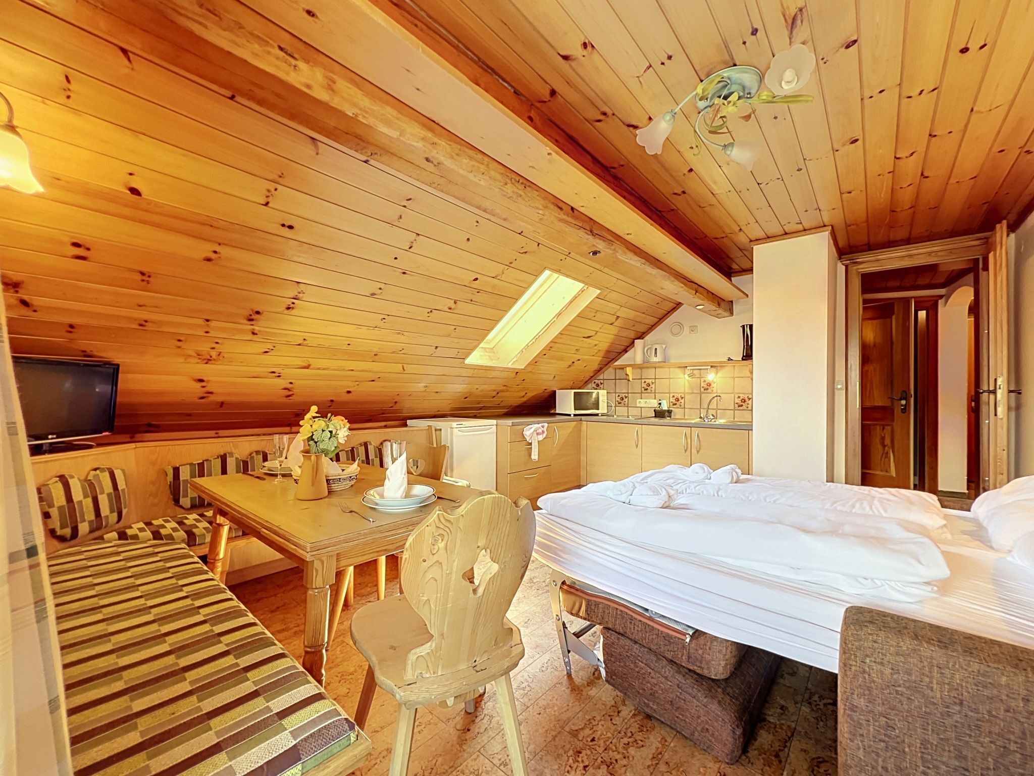 A cozy room with a bed, a dining table, and a television.
