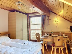 A bedroom with a bed, a wooden desk, a chair, a cross on the wall, and a window with curtains. - Katschberg 21 by Interhome (Sankt Michael im Lungau)