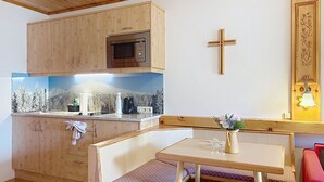 A small kitchenette with a microwave, a sink, and a stove. There is a wooden cross on the wall and a small table with a bench. - Katschberg 18 by Interhome (Sankt Michael im Lungau)
