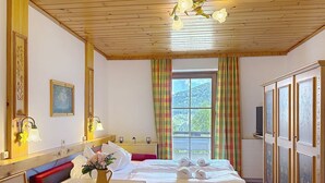 A hotel room with a wooden ceiling, a bed with white linens, a table with a vase of flowers, and a window with curtains. - Katschberg 18 by Interhome (Sankt Michael im Lungau)