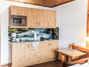 A compact kitchen with wooden cabinets, a microwave, a coffee maker, and a sink. - Katschberg 17 by Interhome (Sankt Michael im Lungau)