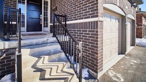A two-story house with a brick exterior, a front door, and a garage. - Modern home away from home in Courtice (Courtice)