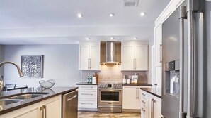 A modern kitchen with stainless steel appliances, white cabinetry, and a patterned floor. - Modern home away from home in Courtice (Courtice)
