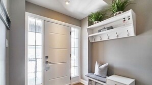 A hallway with a double door, a bench, and a shelf with hooks and items. - Modern home away from home in Courtice (Courtice)