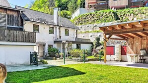 Una propietat residencial amb un jardí ben cuidat, una pèrgola de fusta i un mur de pedra.
