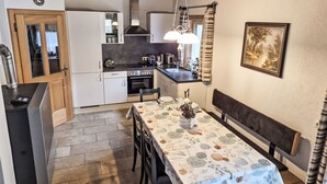 Una cuina compacta amb zona de menjador, bigues de sostre de fusta i un quadre a la paret.