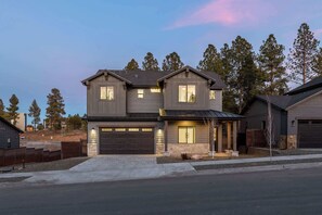 A two-story house with a garage, a covered porch, and a stone foundation. - Luxe Mountain Escape Hot Tub & Pool Table (Flagstaff)