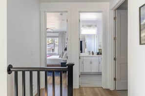 A hallway leading to a bedroom with a view of the outside, a bathroom with a mirror and sink, and a door to another room. - Luxe Mountain Escape Hot Tub & Pool Table (Flagstaff)