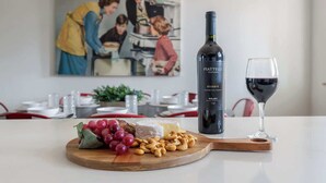 A table with a bottle of Piatti Reserve wine, a glass of red wine, a wooden board with grapes, cheese, and nuts. - Flagstaff Retreat with Hot Tub (Flagstaff)
