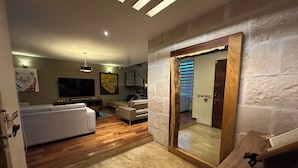 Een moderne woonkamer met een bank, een televisie en een trap naar een andere kamer.
