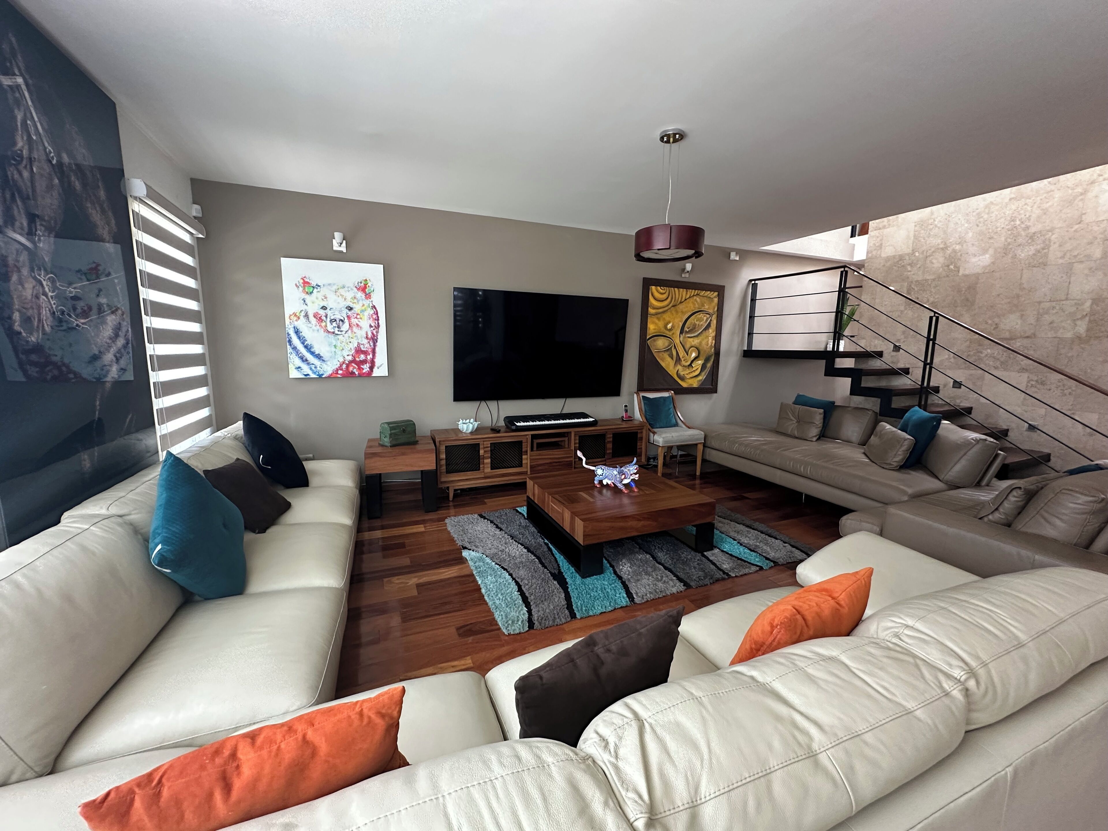 A modern living room with a sofa set, a coffee table, a TV, and artwork on the walls.