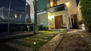Een modern gebouw met een verzorgde tuin, een palmboom en een pad dat naar de ingang leidt.