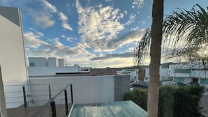 Een modern terras op het dak met glazen hekwerk, uitzicht op de stad en een heldere lucht.