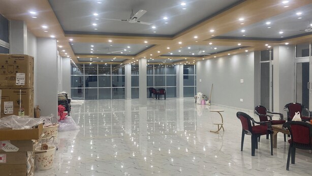 A spacious, well-lit room with a polished marble floor, large windows, and ceiling fans. - Spacious Stay Near Bodh Gaya – AC Rooms, Lawn & Banquet Hall (Bodh Gaya)