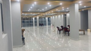 A spacious room with a polished marble floor, large windows, and a ceiling with recessed lighting. - Spacious Stay Near Bodh Gaya – AC Rooms, Lawn & Banquet Hall (Bodh Gaya)