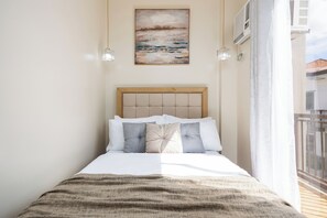 Una cama bien hecha con cabecera de madera, una manta color beige y un cuadro sobre ella.