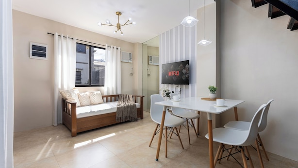 Un salon moderne comprenant un canapé, une table à manger, des chaises, un téléviseur et un escalier.