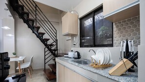 Une cuisine moderne dotée d’un plan de travail en granit, de meubles en bois, d’une cuisinière encastrée et d’une fenêtre avec un pare-feu en carreaux hexagonaux.