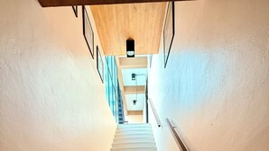 A staircase with a wooden handrail and a light-colored wall. - Karat Residence (Pattaya)
