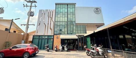 A modern building with a prominent logo, a covered entrance, and several parked motorcycles.