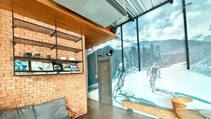 A modern interior with a brick wall, a wooden bench, a sofa, and a mural of cyclists on a snowy mountain. - Karat Residence (Pattaya)