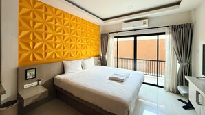 A hotel room with a large bed, a wall-mounted air conditioner, a bedside table with a lamp, and a view of the outside balcony. - Karat Residence (Pattaya)