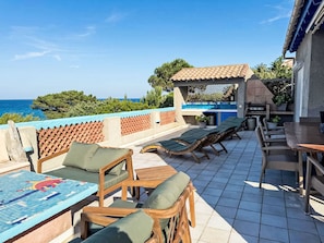 A rooftop terrace with lounge chairs, a table, and a barbecue area overlooking the sea. - Casa Blue by Interhome (Sainte Lucie Porto Vecchio)