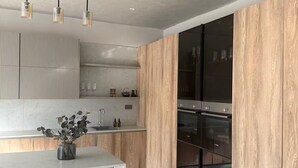 A modern kitchen with a large island, wooden cabinetry, and stainless steel appliances.