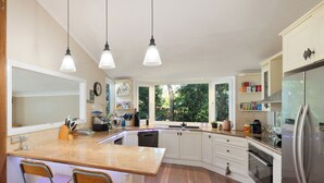 Eine moderne Küche mit weißen Schränken, einer Holzausziehtheke, einem eingebauten Geschirrspüler und einem Edelstahlkühlschrank.