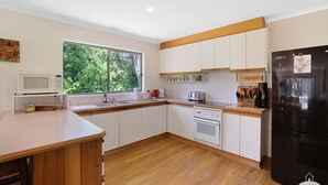 A modern kitchen with white cabinets, a black refrigerator, and a window with a view of greenery. - The Ash, Sandy Point (Sandy Point)