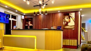 A hotel reception area with a curved counter, a television, and a large poster on the wall. - Emboita Hotels ltd (Nakuru)