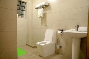 A small bathroom with a toilet, a sink, and a shower. - Emboita Hotels ltd (Nakuru)