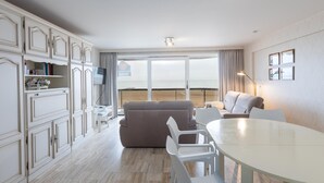 Una habitación de hotel moderna con un balcón grande, una zona de comedor y una sala de estar.