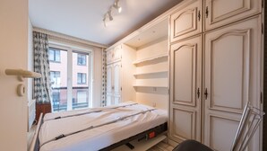 Un dormitorio con una cama, una silla y un armario.
