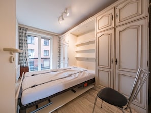 Ein Schlafzimmer mit einem Bett, einem Sessel und einem Kleiderschrank.