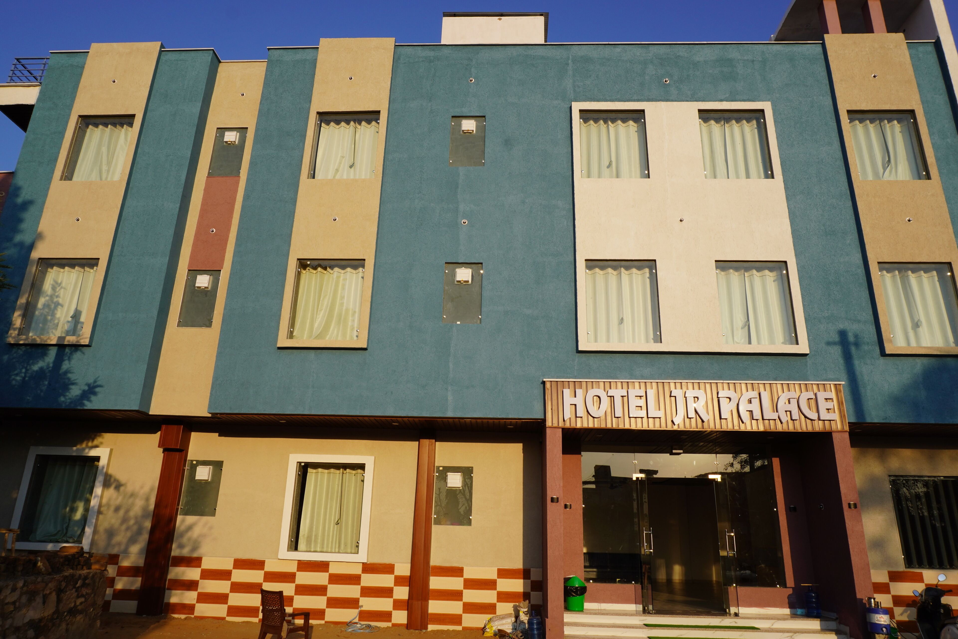 Un hotel de varios pisos con un diseño a cuadros en la base, un letrero que dice 'HOTEL IR PALACE' y una entrada de vidrio.
