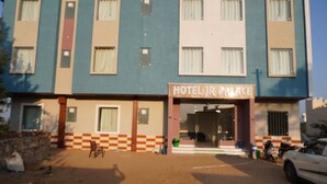 Ein Hotel mit Schachbrettmuster-Fassade, einem Schild mit der Aufschrift "HOTEL JR PALACE" und einem unbefestigten Boden.