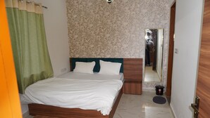 Ein Schlafzimmer mit einem hölzernen Bett, weißer Bettwäsche, einem grünen Vorhang, einer Wand mit Muster und einem Spiegel.