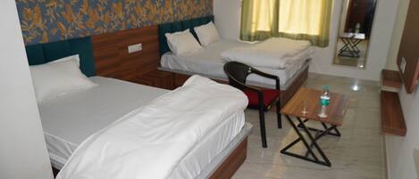 Habitación de hotel con dos camas, una mesita con una botella, una silla y un espejo en la pared.