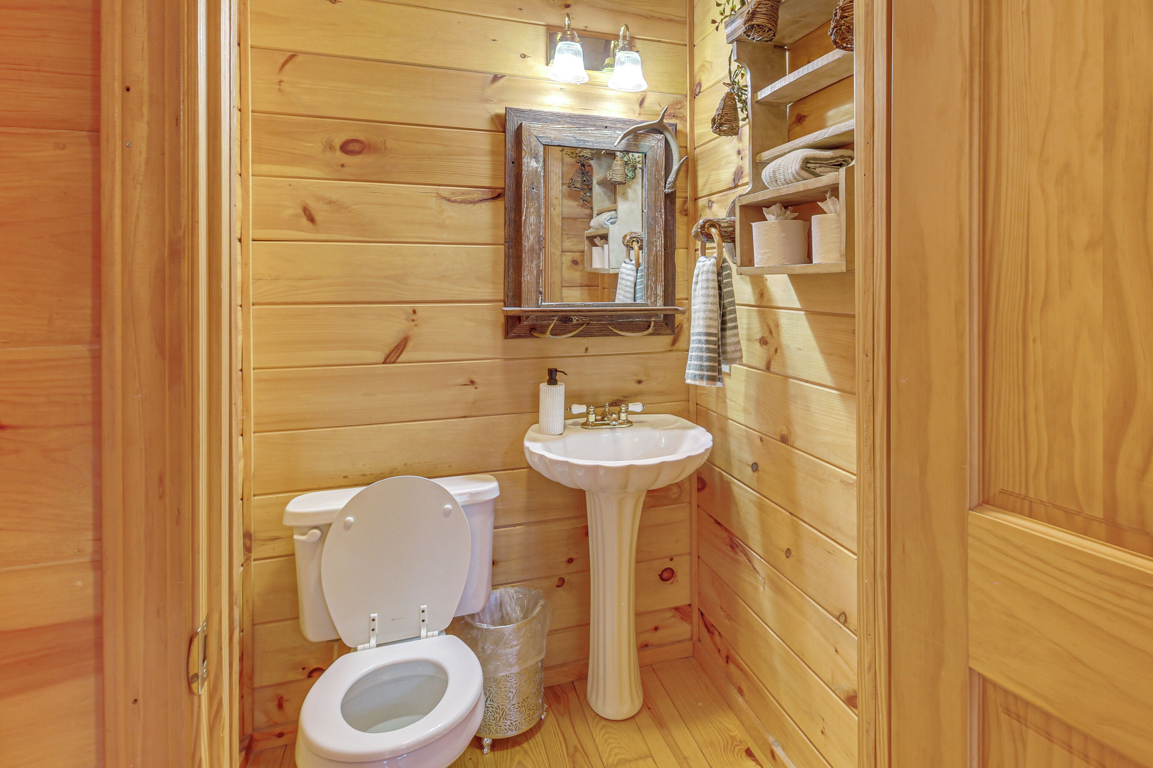 Un baño con paneles de madera, un inodoro, un lavamanos y un espejo.