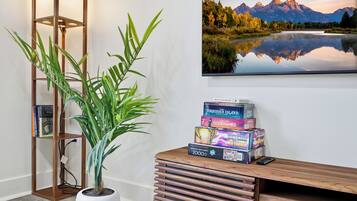 A room with a wooden desk, a potted plant, and a framed landscape painting.